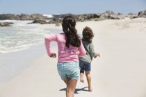 Игривые дети бегают по песчаному пляжу — стоковое фото