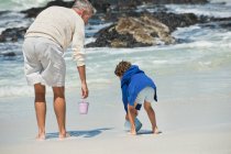 Хлопчик грає зі своїм дідом на пляжі — стокове фото