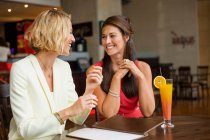 Two female friends smiling at each other in a restaurant — Stock Photo