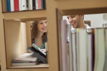 Casal escolher livros de estantes na biblioteca — Fotografia de Stock