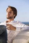 Thoughtful young man drinking wine on coast — Stock Photo