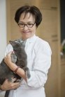 Reife Frau hält Katze und lächelt — Stockfoto