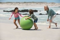 Donna che gioca con i suoi nipoti sulla spiaggia — Foto stock