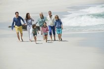 Familia feliz caminando en la playa de arena - foto de stock