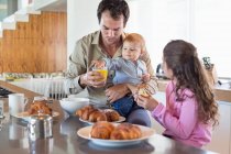Famille prenant le petit déjeuner à un comptoir de cuisine — Photo de stock