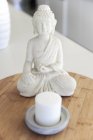 Close-up of Buddha statue with candle on table — Stock Photo