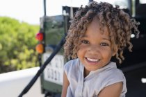 Porträt eines kleinen Mädchens, das draußen sitzt und lächelt — Stockfoto