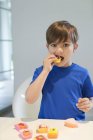 Boy eating sweet cupcake and looking at camera — Stock Photo