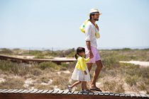 Uomo con la figlia che cammina su una passerella sulla spiaggia — Foto stock