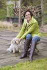 Donna seduta su sgabello in legno all'aperto con cane — Foto stock