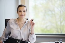 Портрет уверенной деловой женщины, улыбающейся в офисе — стоковое фото