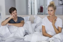 Молодая пара, сидящая на кровати с трудностями в отношениях — стоковое фото