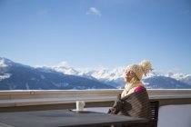 Journée de la femme rêvant avec une tasse de café sur la terrasse avec vue sur les montagnes, Crans-Montana, Alpes suisses, Suisse — Photo de stock