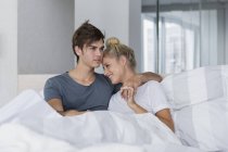 Glückliches junges Paar entspannt sich morgens im Bett — Stockfoto