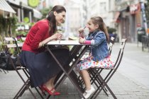 Donna felice e piccola figlia che beve in un caffè marciapiede — Foto stock