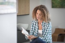 Крупним планом зосереджена молода жінка читає книгу вдома — стокове фото