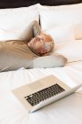 Man resting on bed with laptop in hotel room — Stock Photo