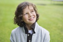 Крупный план мальчика, улыбающегося на зеленом поле — стоковое фото