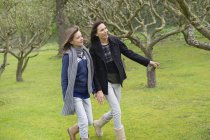 Mulher com filha adolescente andando no pomar — Fotografia de Stock