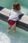 Linda niña jugando en la piscina infinita - foto de stock