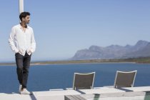 Чоловік спирається на колону на терасі на березі озера — стокове фото