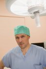 Cirujano masculino de pie en quirófano - foto de stock
