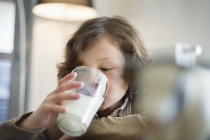 Close-up de menino bebendo leite de vidro na cozinha — Fotografia de Stock