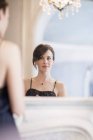 Riflessione di donna elegante in abito da notte guardando specchio — Foto stock