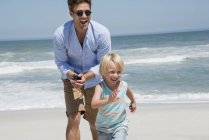 Молодий чоловік грає з сином на літньому пляжі — стокове фото