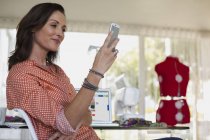 Женщина модельер с помощью мобильного телефона в студии — стоковое фото