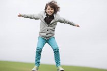Портрет игривого мальчика, прыгающего в осеннем поле — стоковое фото