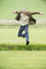 Fröhlicher reifer Mann springt in grünes Feld — Stockfoto