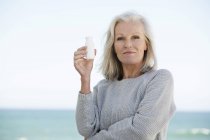 Ritratto di donna che tiene una bottiglia di bevanda probiotica sulla spiaggia — Foto stock