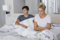 Junges Paar sitzt mit Beziehungsschwierigkeiten im Bett — Stockfoto