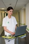 Portrait of female nurse using laptop in hospital corridor — Stock Photo