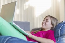 Mädchen liegt auf Sitzsack und benutzt Laptop — Stockfoto
