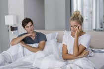 Молода пара сидить на ліжку з труднощами у відносинах — стокове фото
