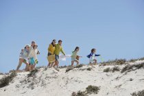 Famille heureuse marchant sur la plage de sable en été — Photo de stock