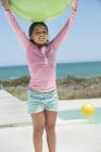 Усміхнена маленька дівчинка тримає фітнес-кулю на пляжі — стокове фото