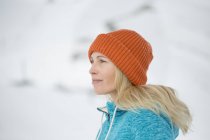 Gros plan de la femme en bonnet tricoté regardant loin en hiver à l'extérieur — Photo de stock