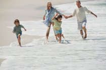 Дети играют со своими бабушкой и дедушкой на пляже — стоковое фото