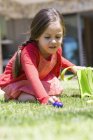 Girl picking up Easter eggs on green lawn — Stock Photo
