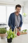 Portrait d'homme souriant hachant des légumes dans la cuisine — Photo de stock
