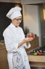 Portrait of woman in chef costume holding jar of tomato sauce — Stock Photo