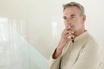 Thoughtful mature man standing in front of wall — Stock Photo