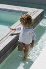 Linda niña jugando en el agua en la piscina infinita - foto de stock