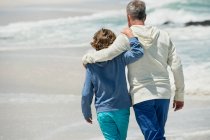 Чоловік ходить зі своїм онуком на пляжі — стокове фото