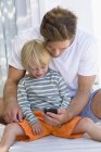 Щасливий батько і син використовують телефон — стокове фото