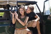 Жінка з хлопцем зйомки з відеокамерою перед відкритим фургоном — стокове фото