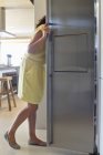 Женщина смотрит в холодильник на современной кухне — стоковое фото